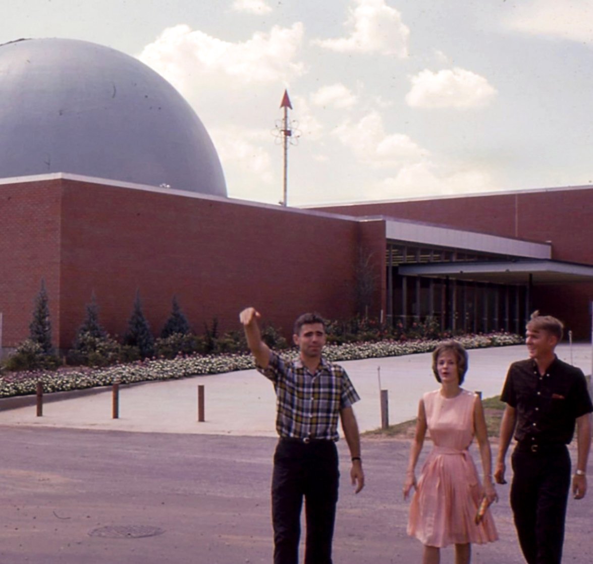 Three people stand in front of a domed building