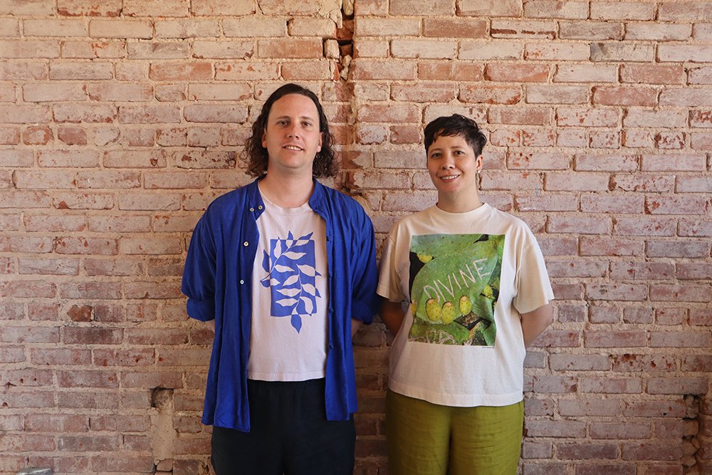 Artists Dylan Cale Jones and Isa Rodriguez pose in front of a brick wall