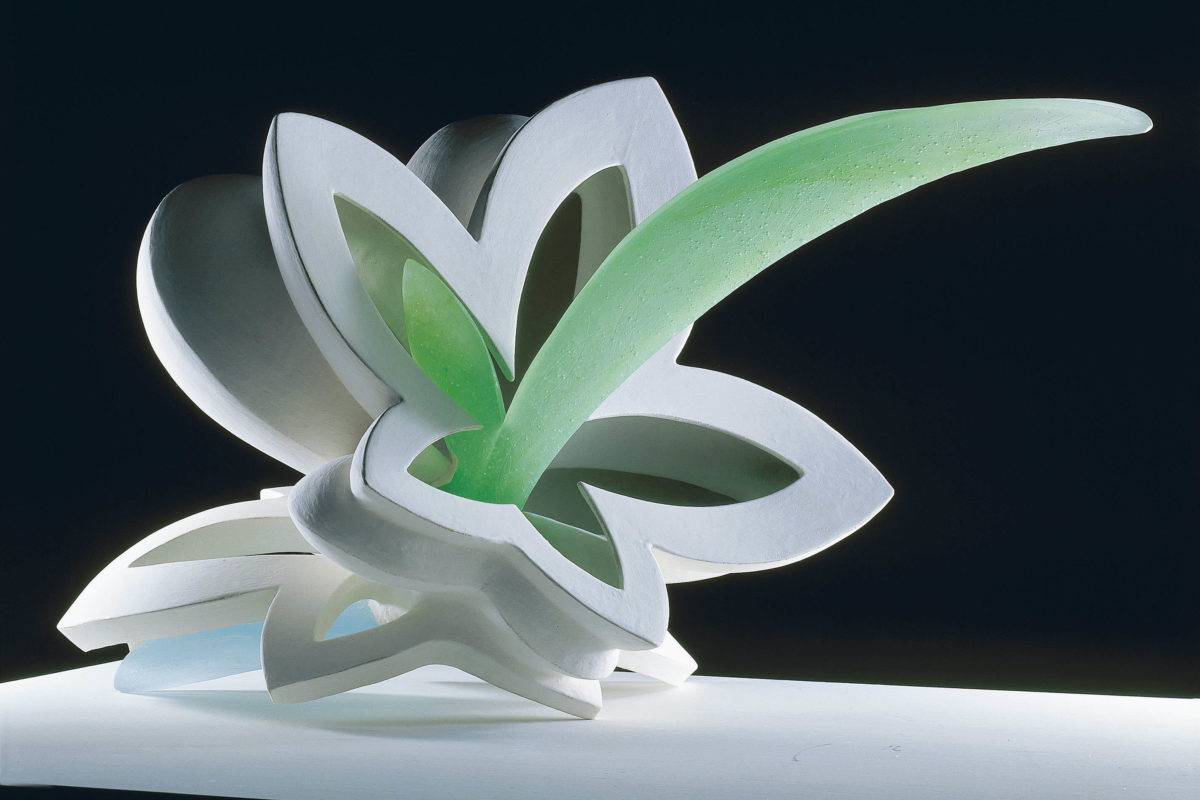 A sculpture of a white lily with a green center, resting on a black background