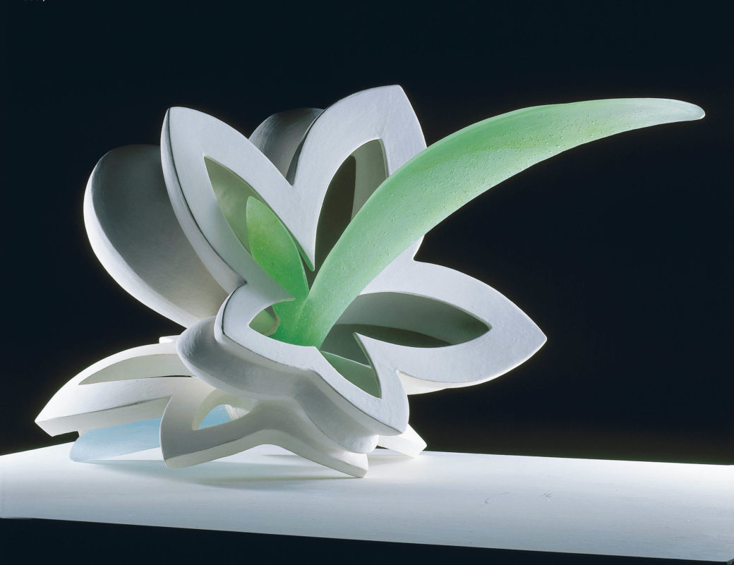 A sculpture of a white lily with a green center, resting on a black background