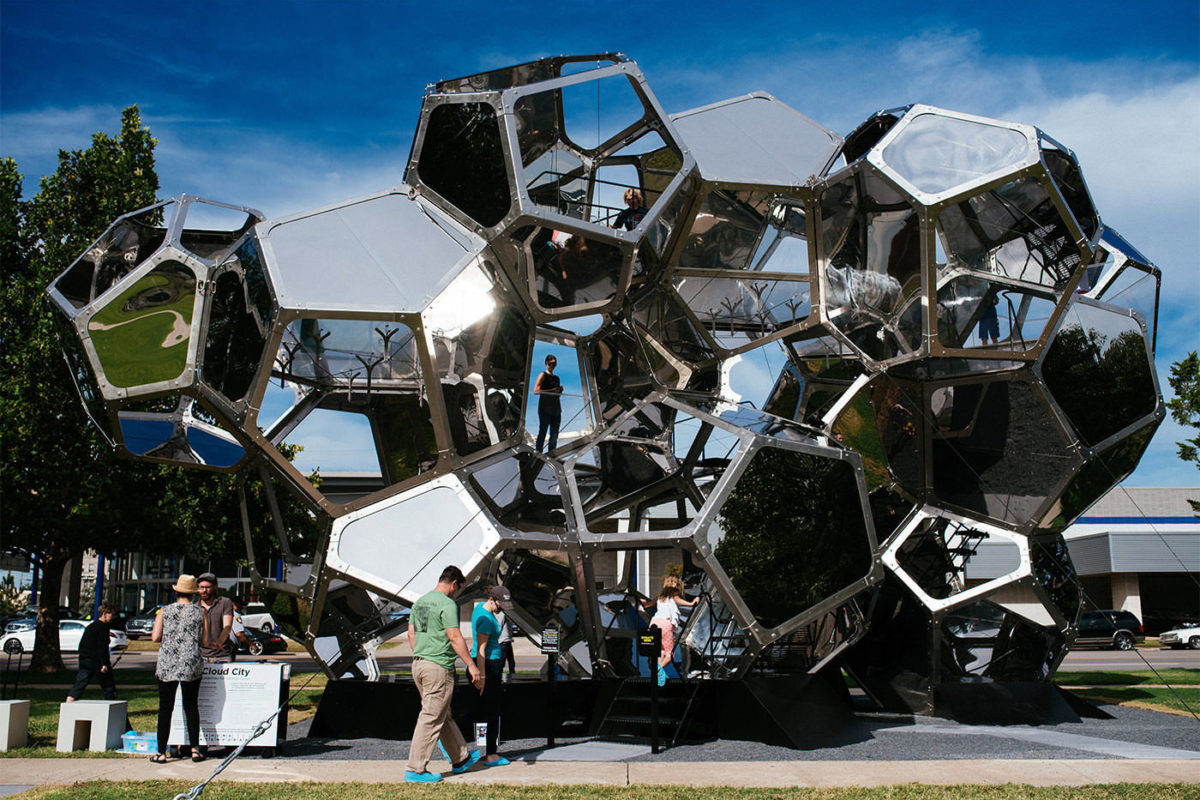 A photo of a large glass and metal sculpture with various compartments for people to climb in and through