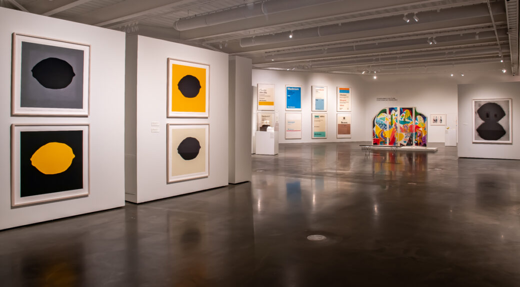 A gallery filled with food-related artworks, including prints of lemons, large prescription-style labels detailing various foods and a colorful folding set of panels