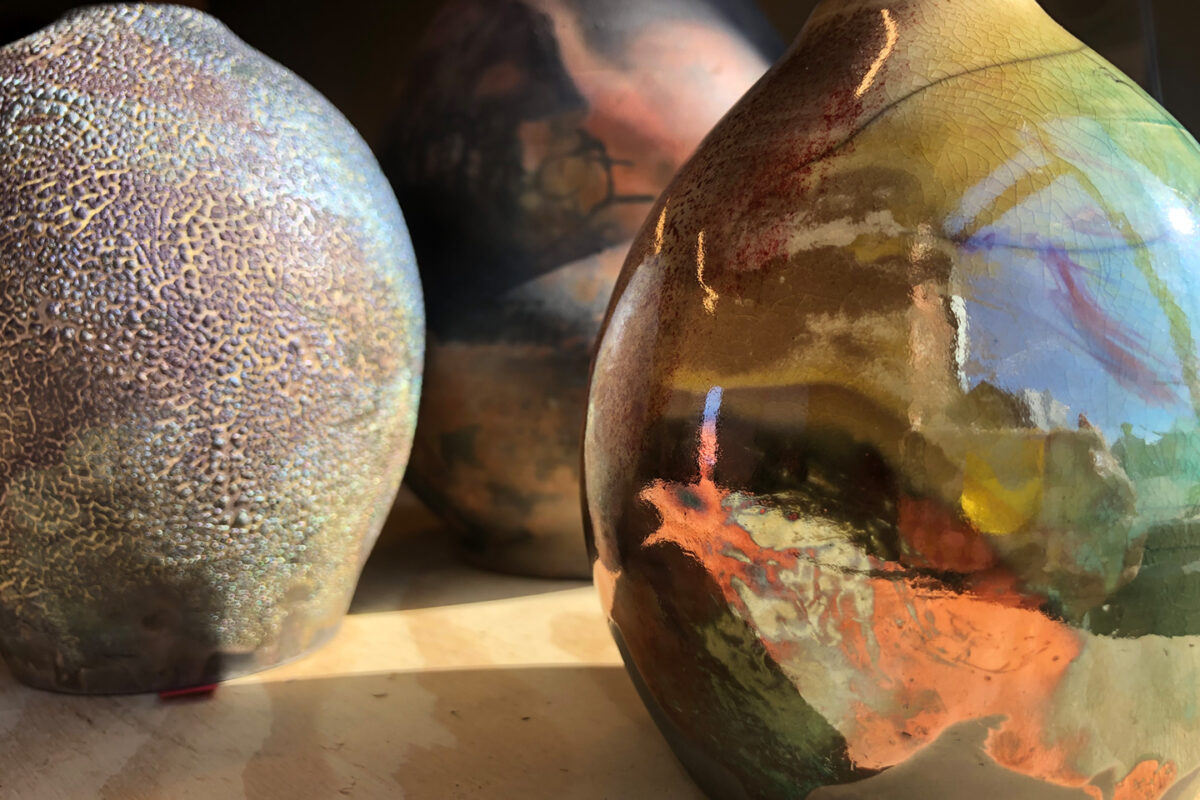 Close up of three ceramic vessels with a variety of shiny and textured glazes