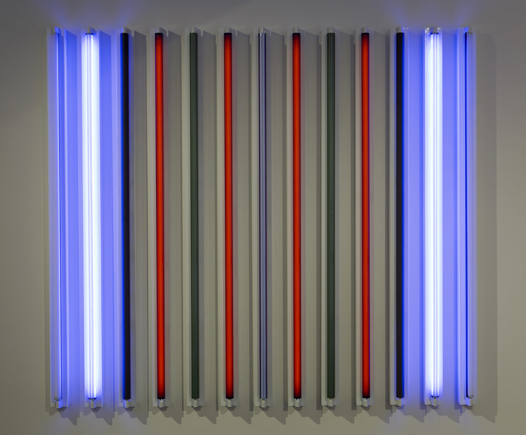 Thirteen fluorescent lights in perfect parallel lines form a square; two blue lights glow on each end