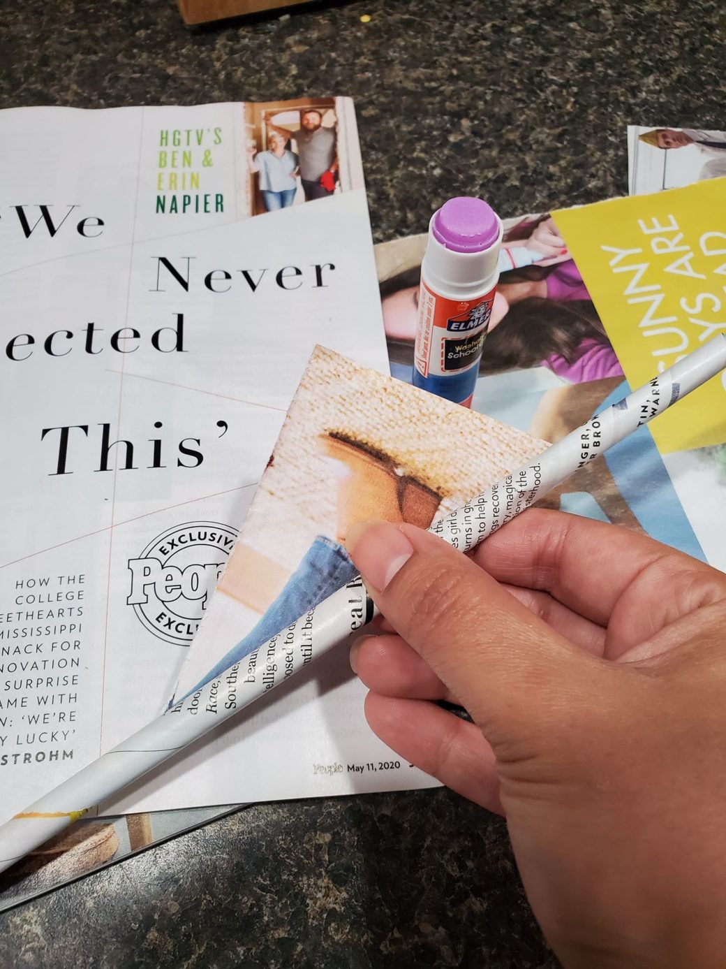 A hand manipulates pages from a magazine for an art project