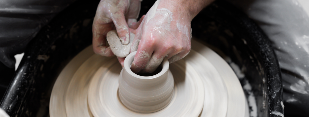 Hands manipulating clay on pottery wheel