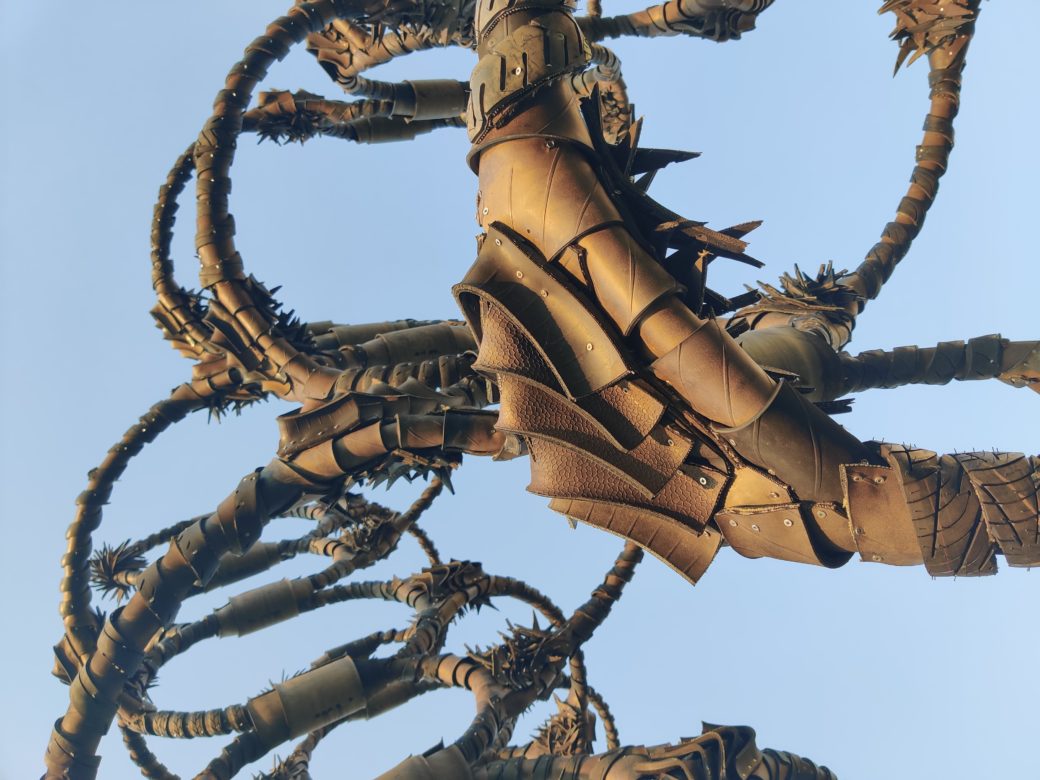 Detail of a sculpture of rubber tires twisted into multiple loops over a metal frame at golden hour
