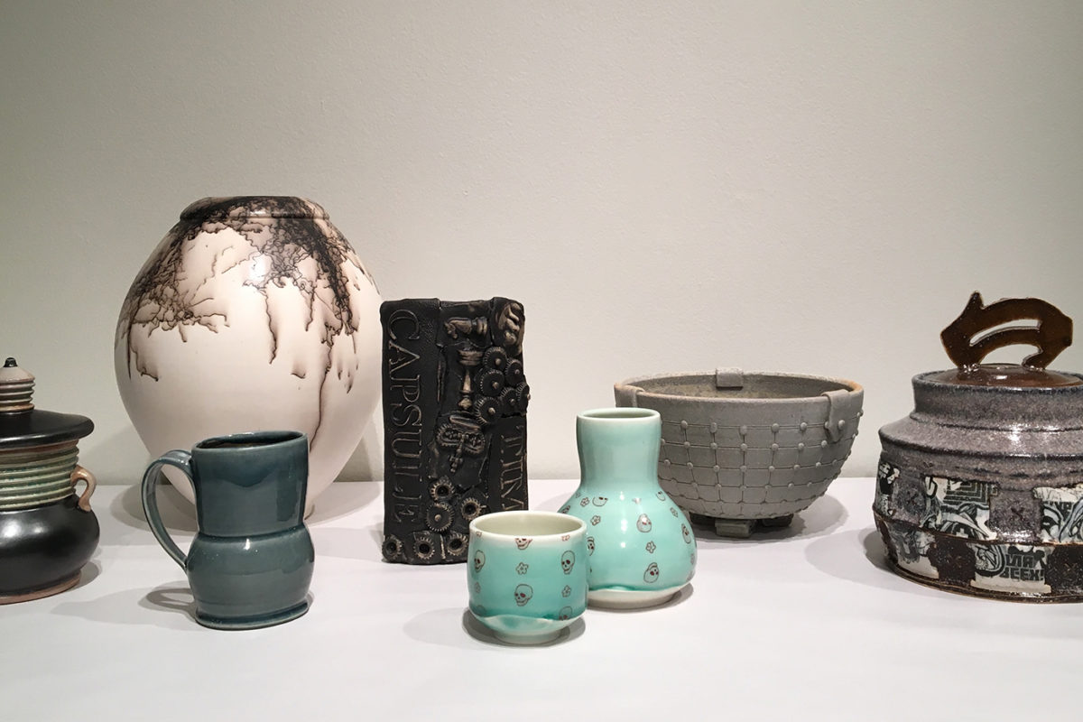 A display of eight ceramic pieces glazed in either gray, white, or blue