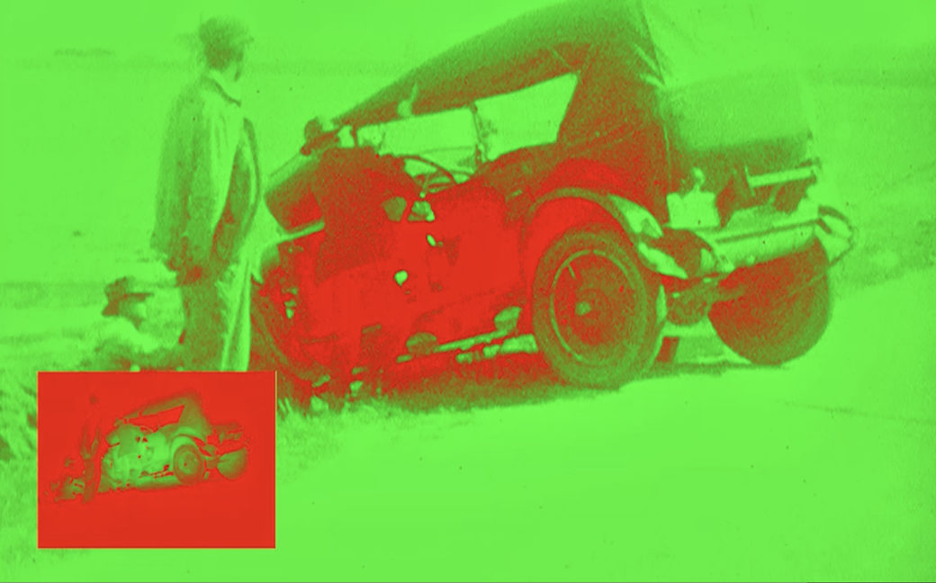 Film still -- altered to appear in lime green and bright red -- shows two figures standing near an old buggy-style car