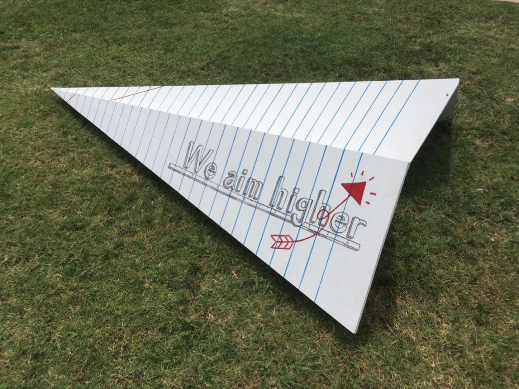 Notebook paper forms a paper airplane reading “We aim higher” under a red arrow