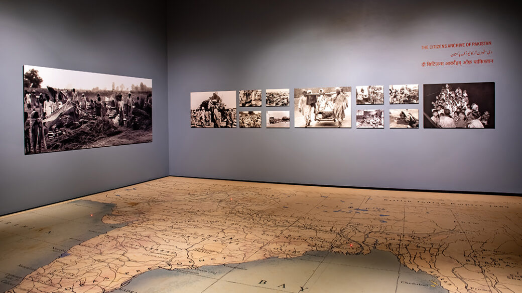 A map is printed on the floor. Black and white photographs hang on the walls.