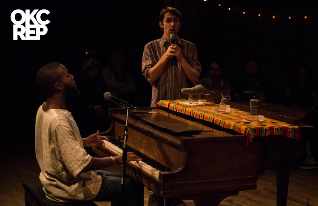 A person plays an old piano decorated with several objects while another individual holds a microphone