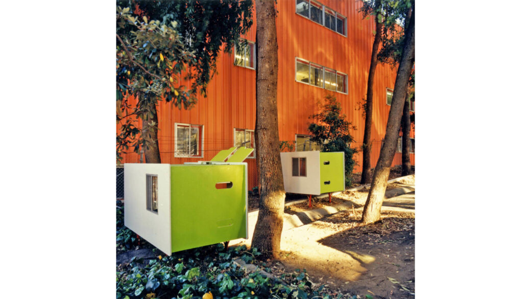 Two white and bright green rectangular pods sit next to a larger orange building