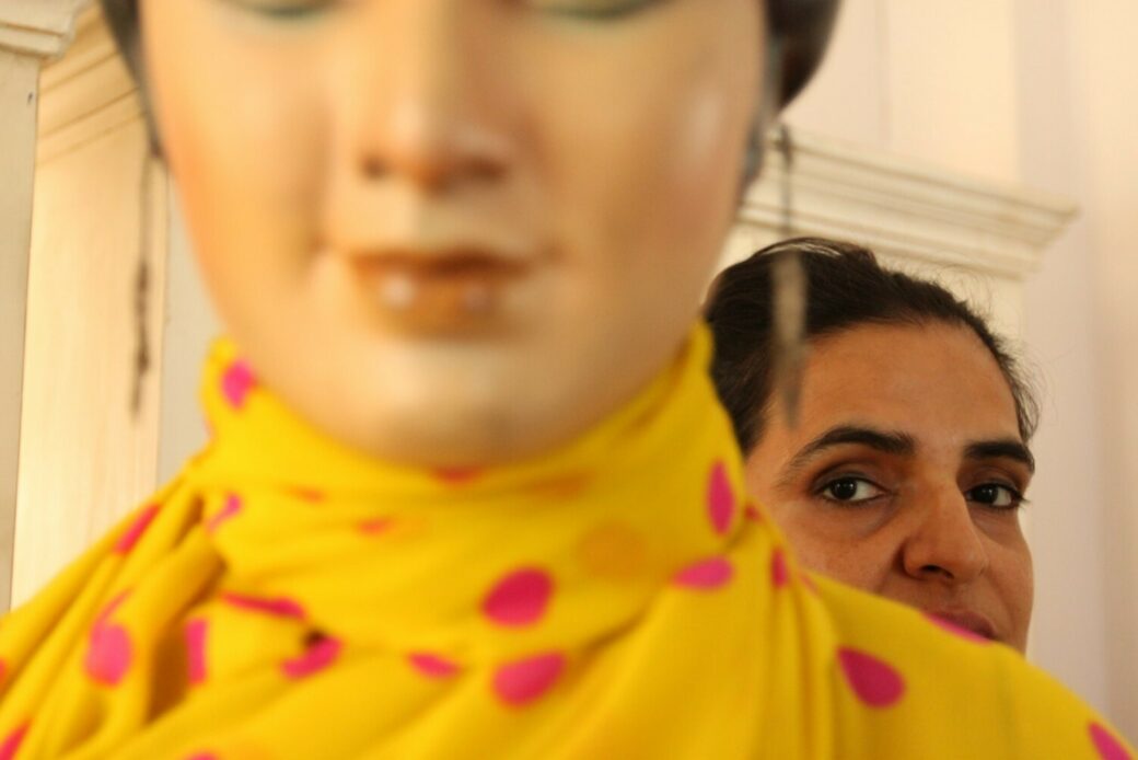 Close-up view of a woman looking over a mannequin's shoulder