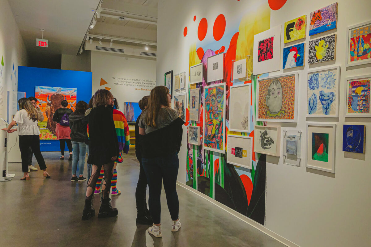 Students walk through a space with a variety of brightly colored decorations and framed artwork on the walls.