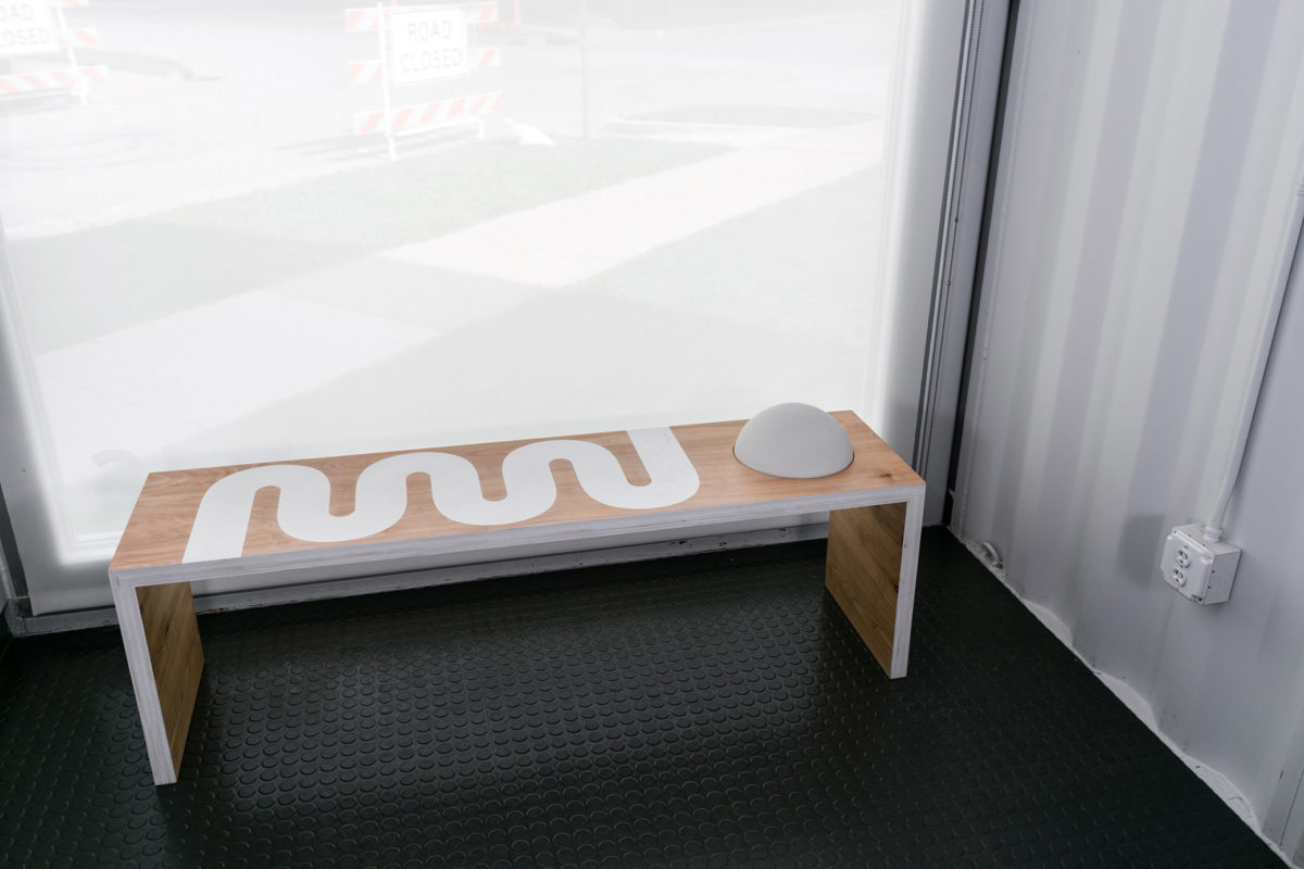 A wooden bench with white trim and curvy patterns features an opaque semi-sphere