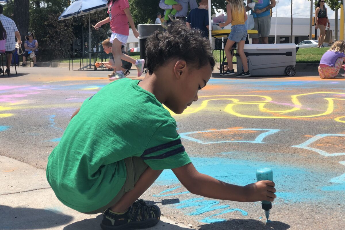 A child draws on pavement with chalk