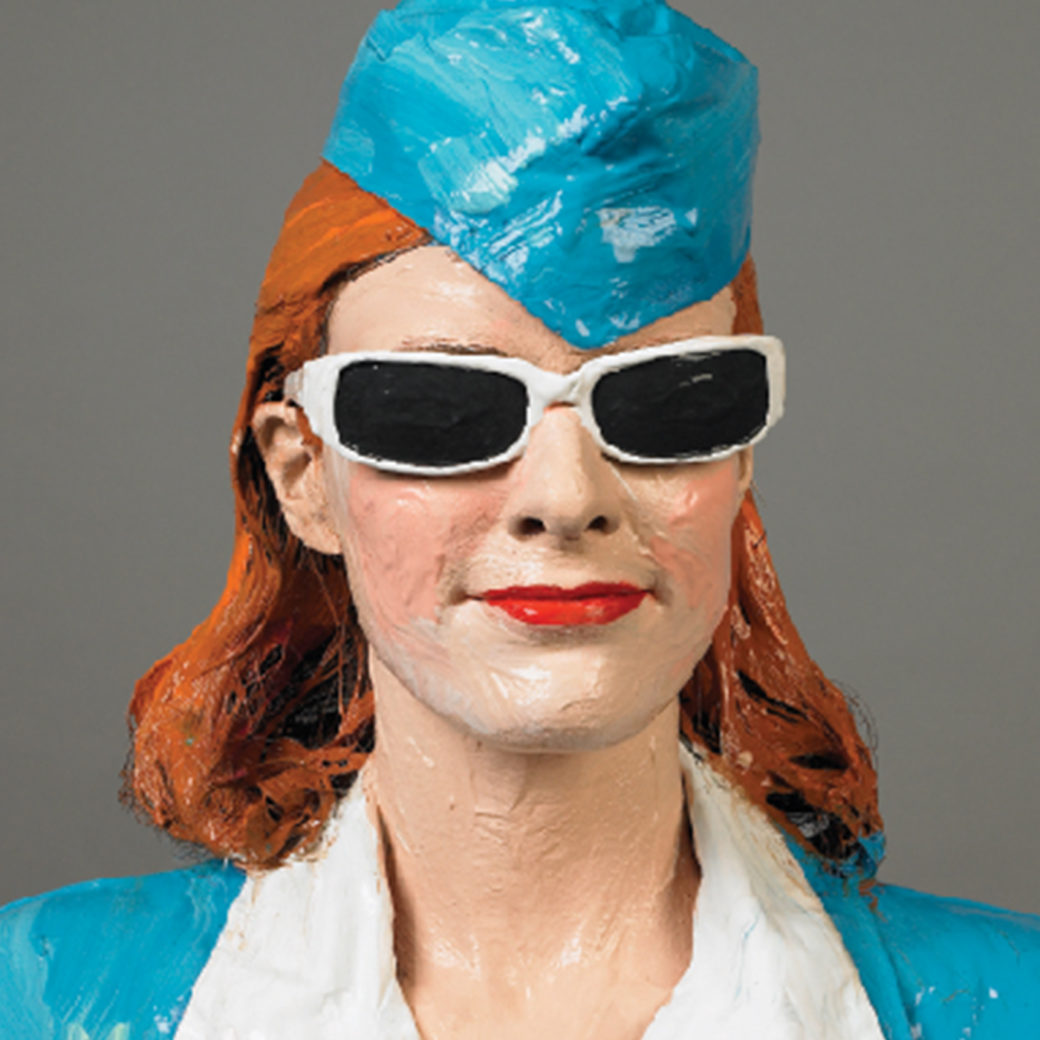 light skinned woman with red hair wearing white sunglasses and a turquoise suit and 50s style stewardess hat