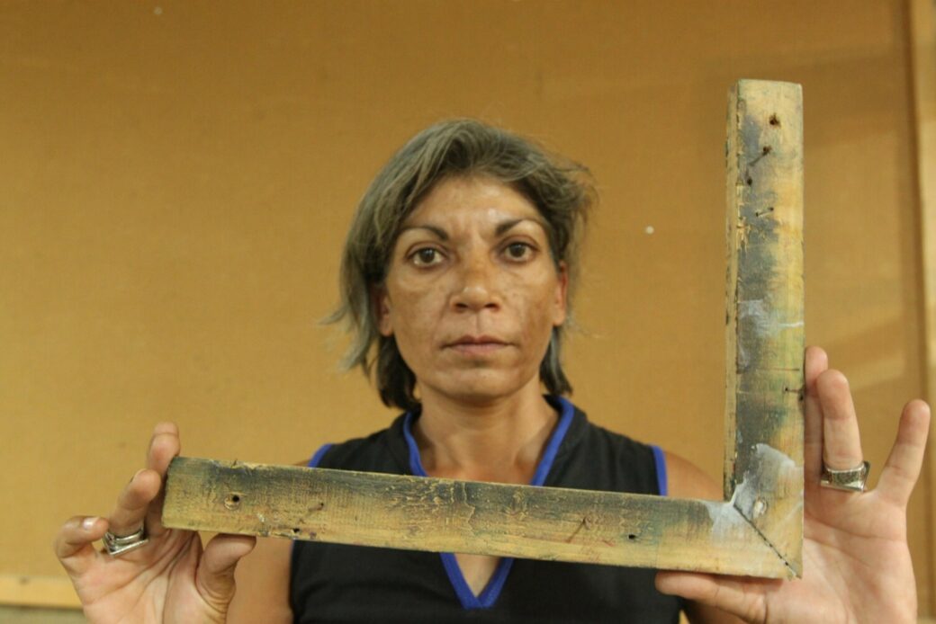 A gray-haired woman holds a carpenter's square