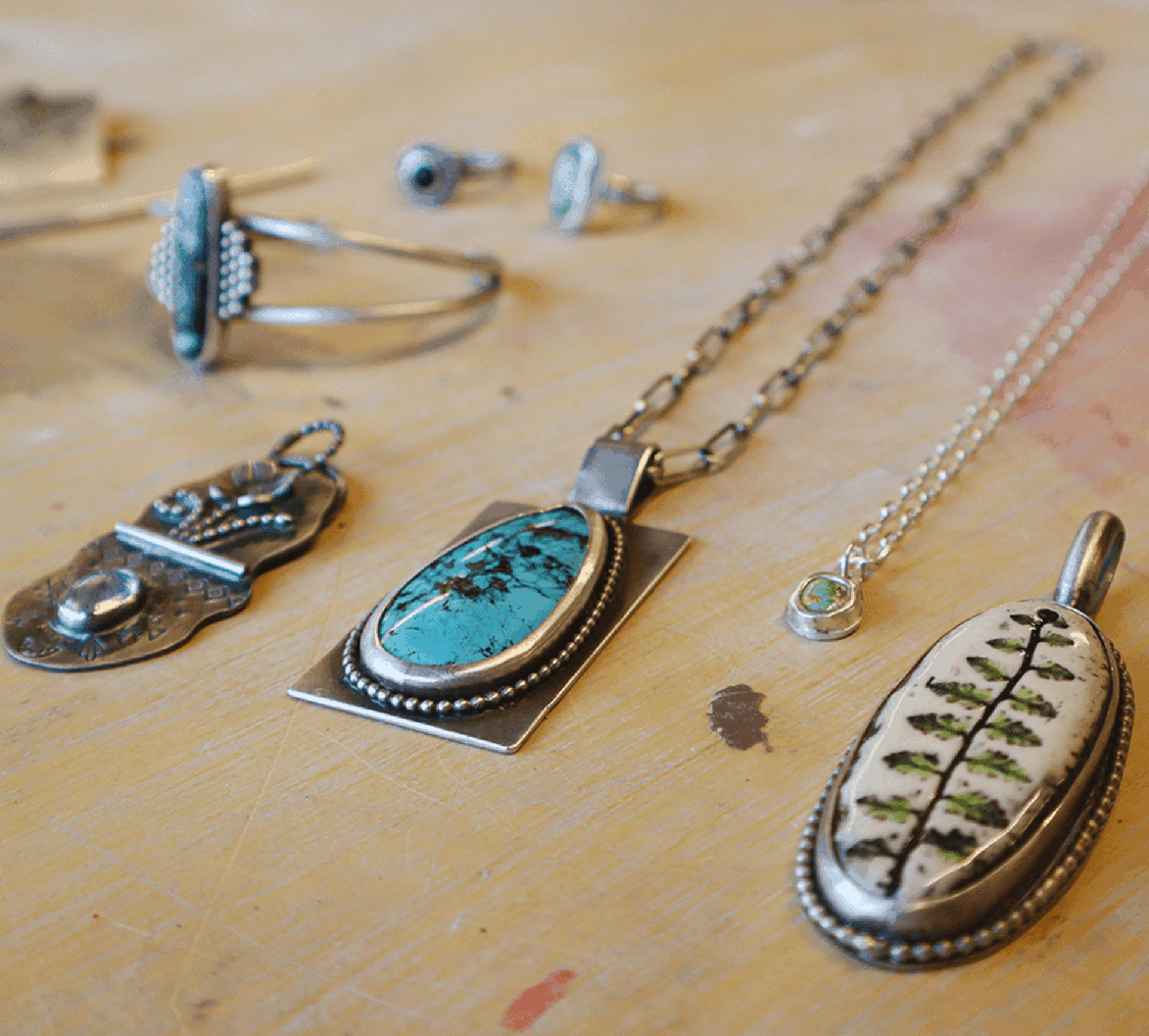 Various metal and stone necklaces, rings and a bracelet on a wooden surface