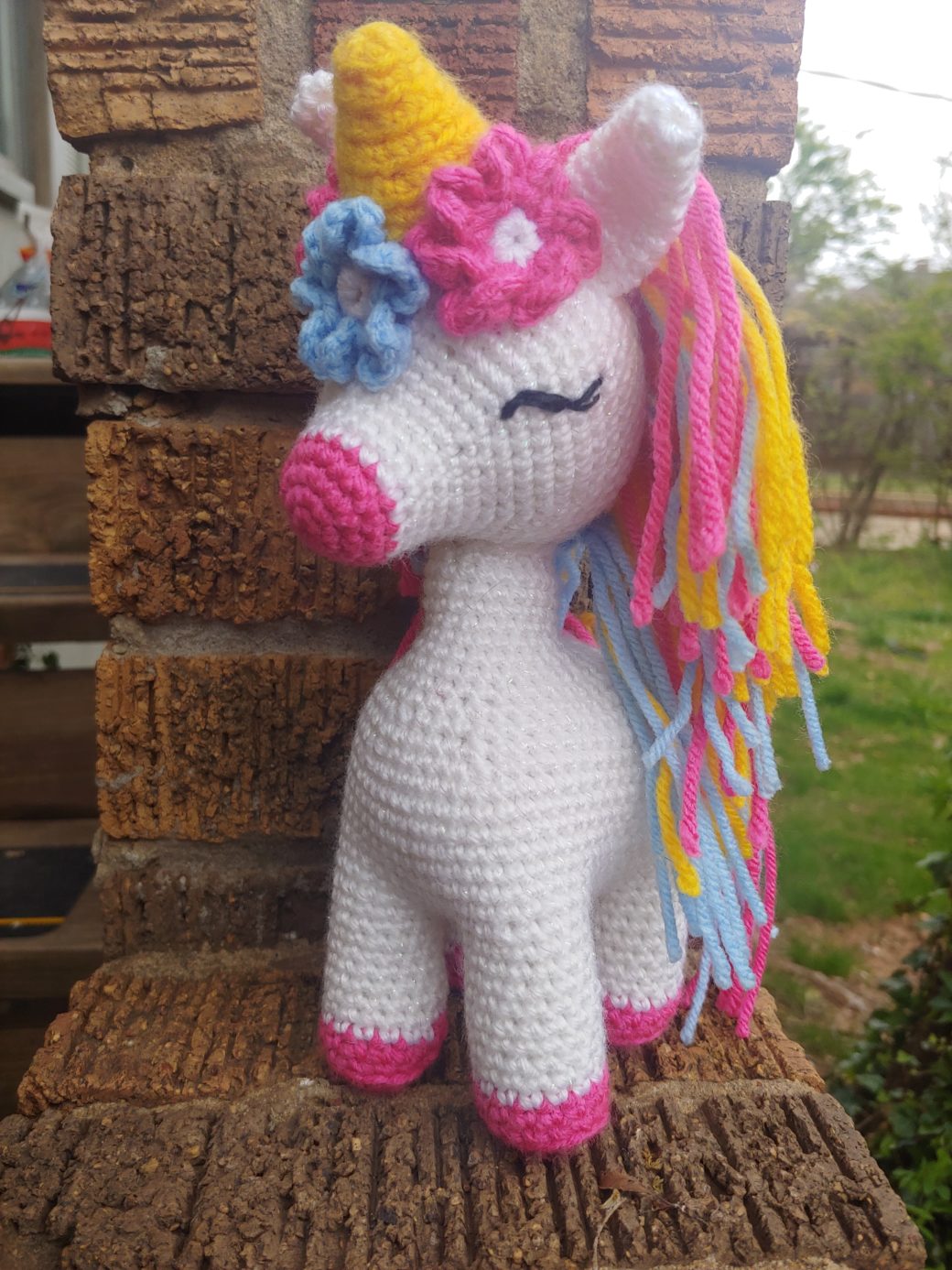 image of a crochet 3-D unicorn with pink hair and a yellow horn.