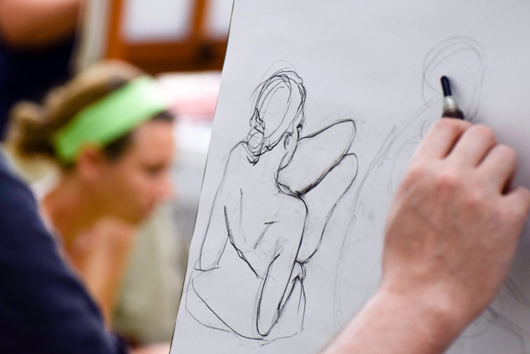Image of a hand drawing the outlines of a female figure