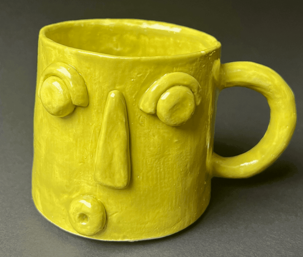 A yellow mug with an abstract face design