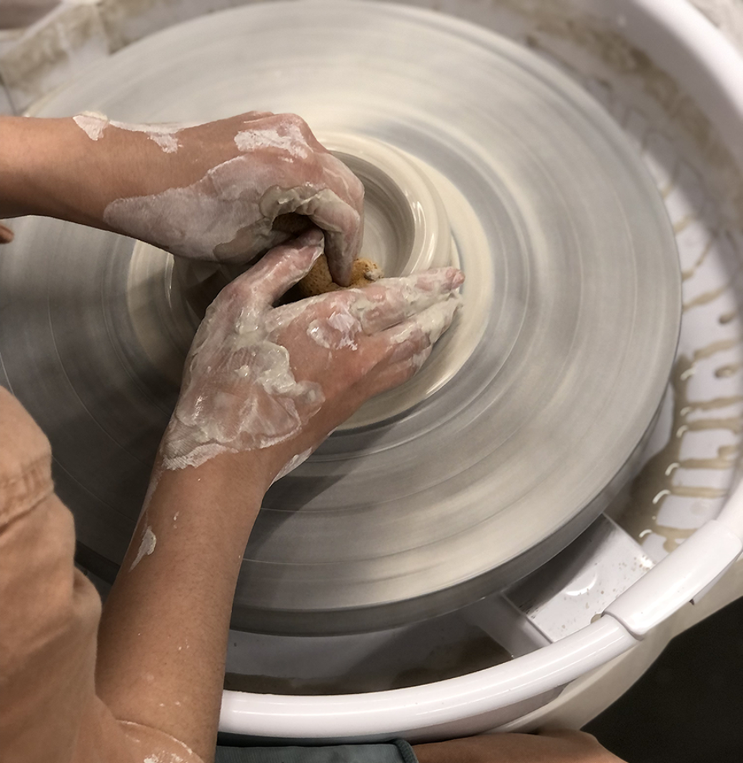Close up view of hands manipulating clay on a wheel