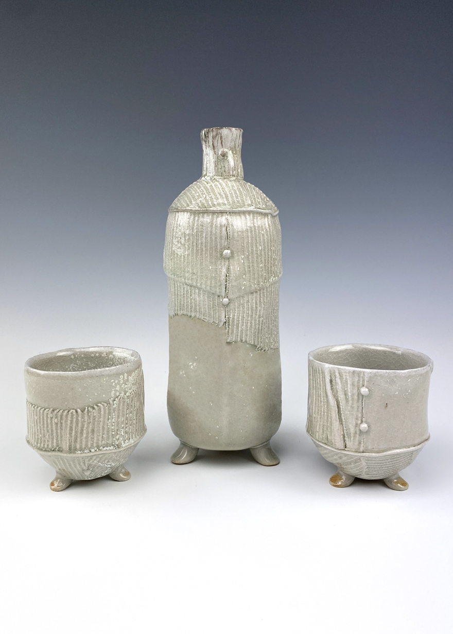 Cream-colored ceramic bottle with two matching cups