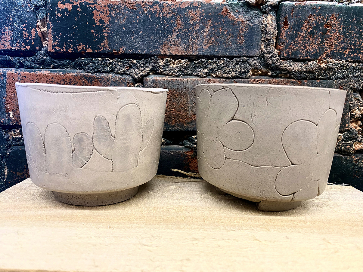 Two clay cups with cactus and flower designs