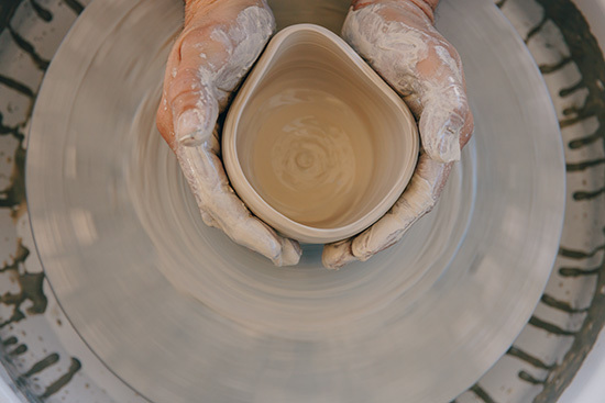 Overhead view of man's hands shaping clay on a ceramic's throwing wheel
