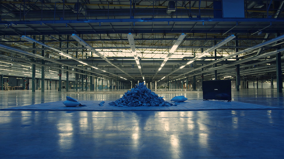 A large pile of blue paper sits on a tile floor built in a giant warehouse