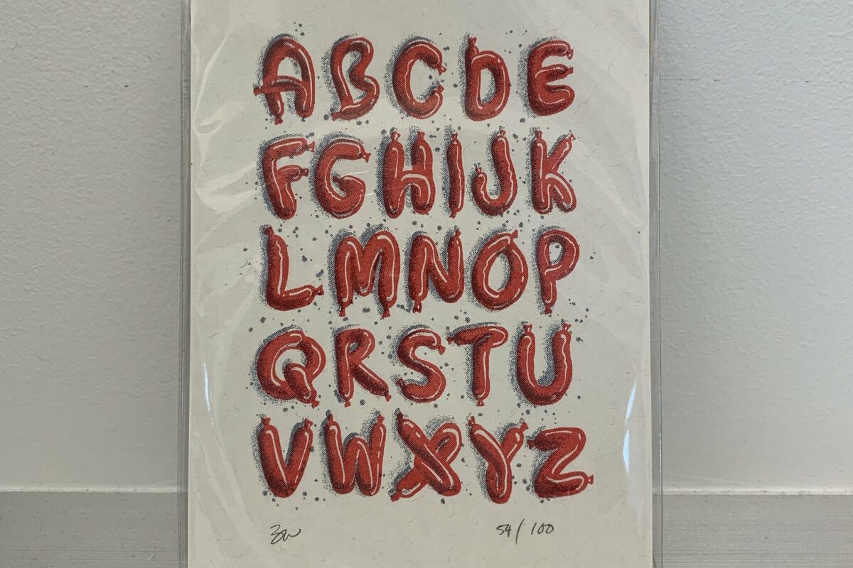 A white greeting card features the alphabet made of twisted, red-brown, balloon-like sausages