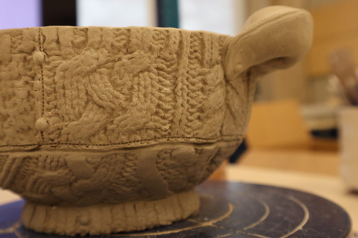 A ceramic bowl with a cable-knit pattern pressed into the clay sits on a table