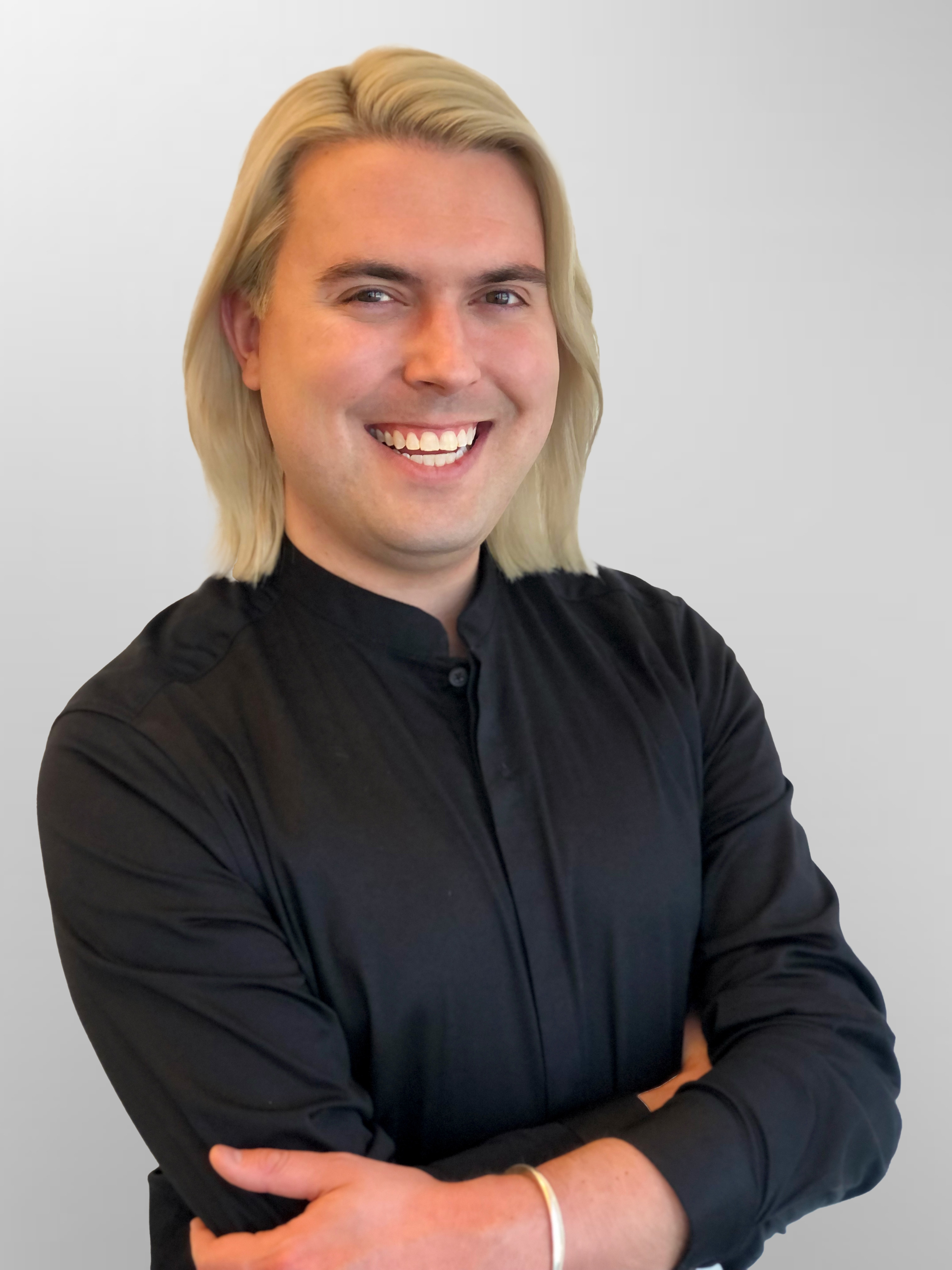 A person with shoulder-length blonde hair wearing a black shirt