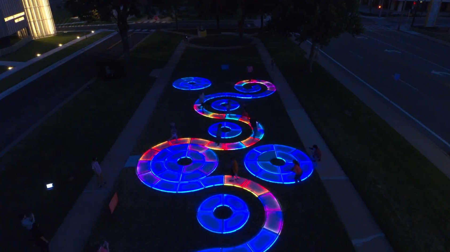 An aerial photo depicts a winding light sculpture at night