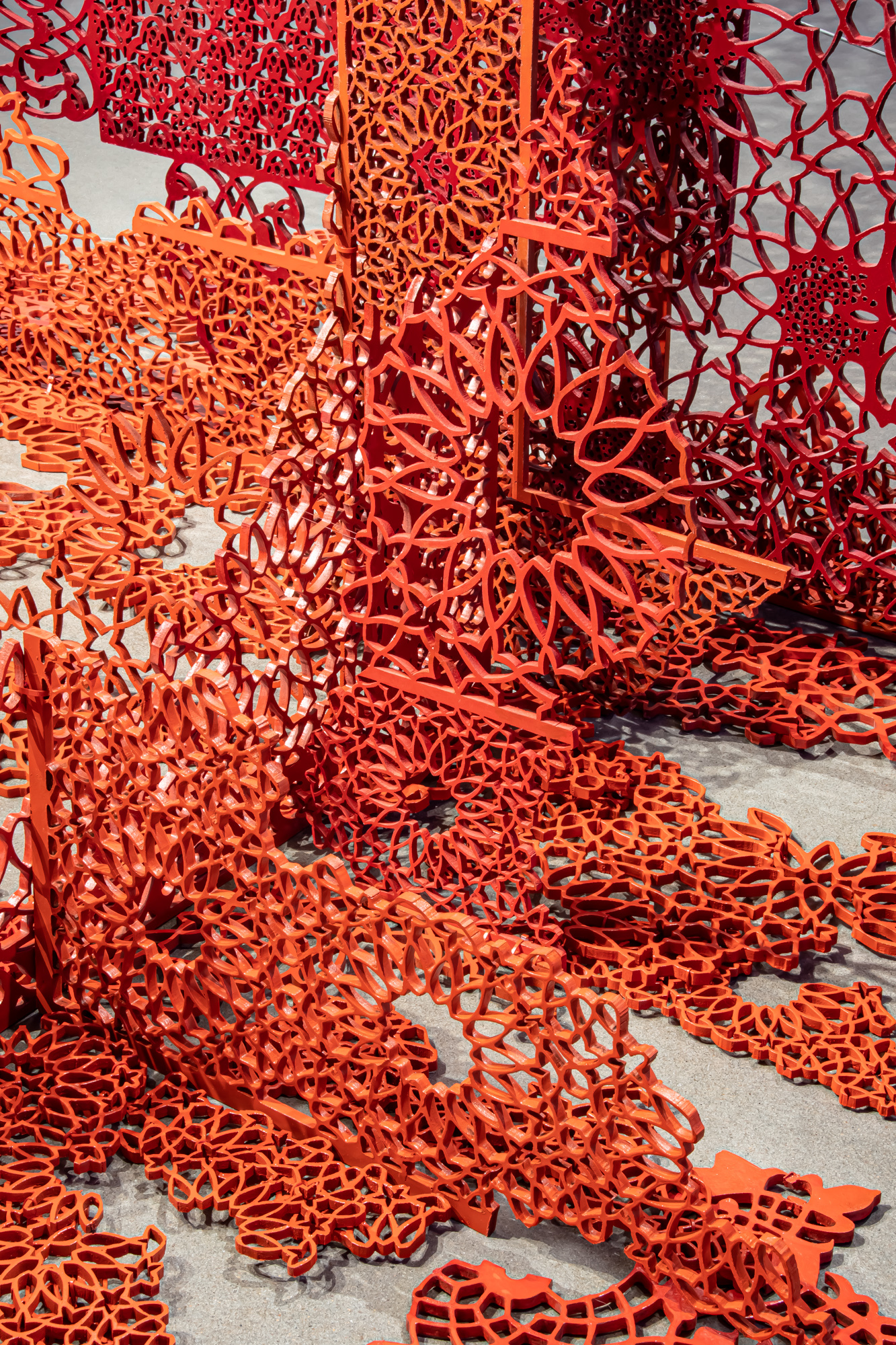 A detail photo of intricately-cut plastic screens in vivid red and orange