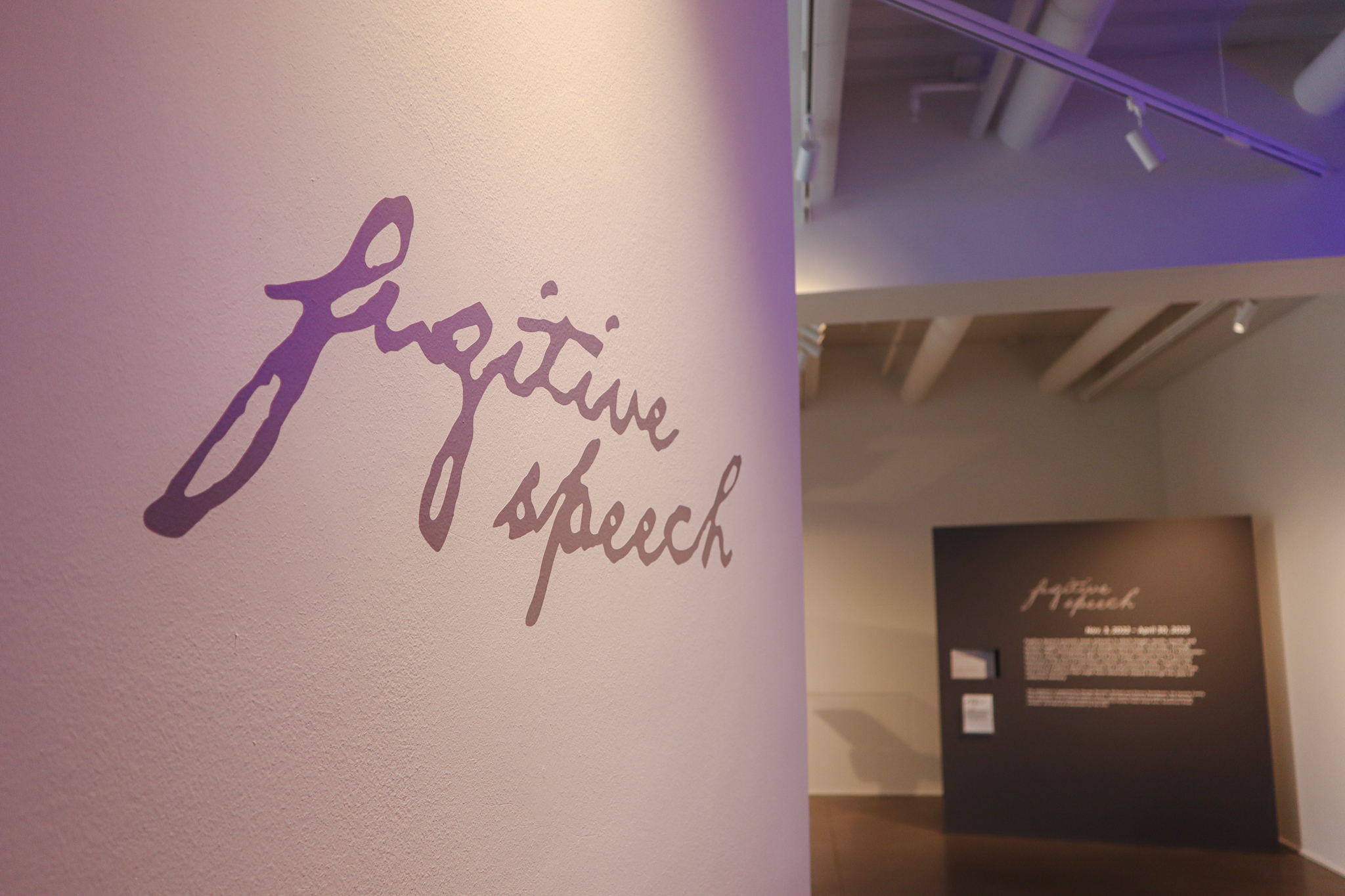 Written in lowercase cursive is 'fugitive speech' in gray on a white wall.