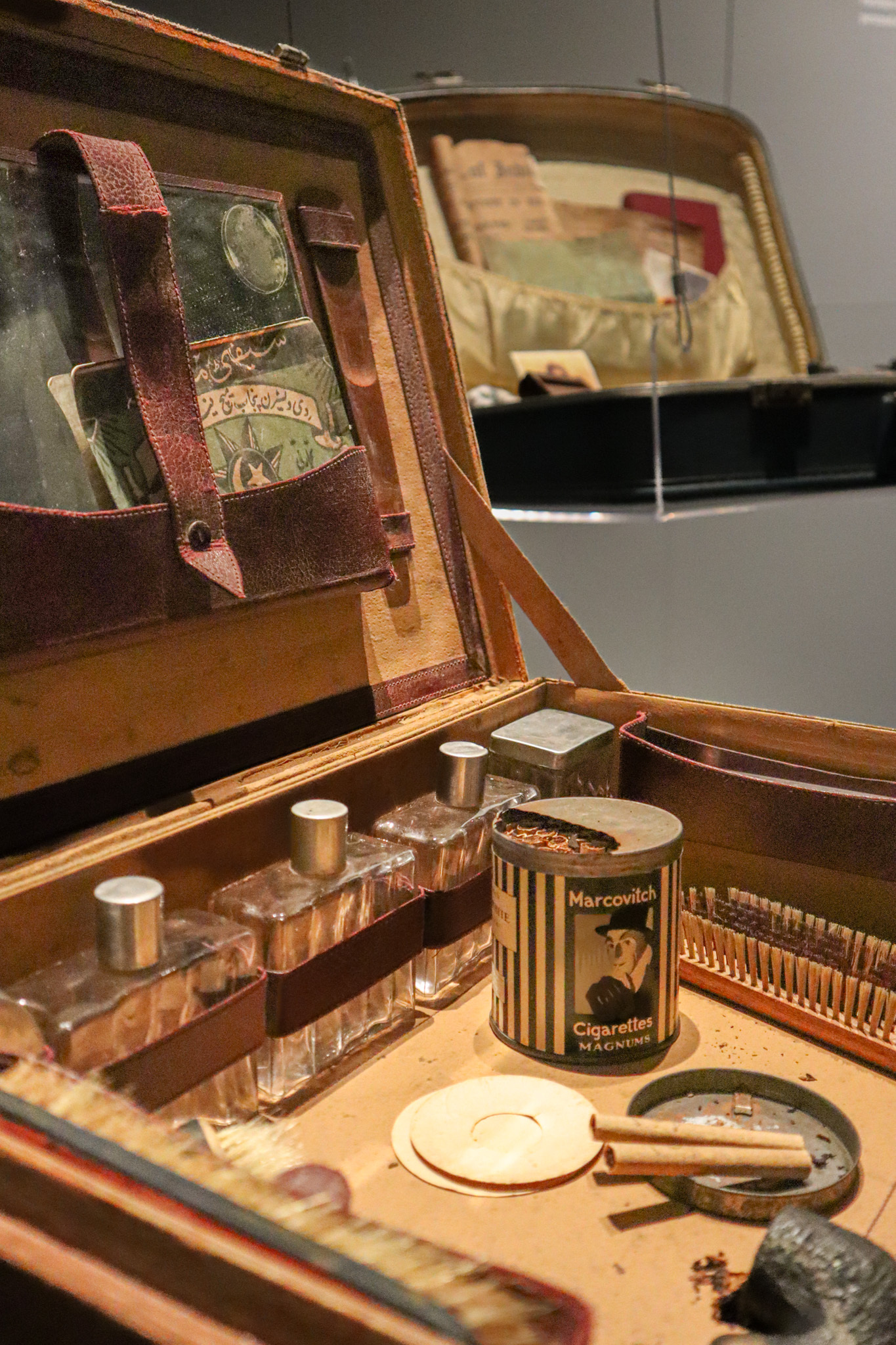 An open suitcase shows a tube of cigarettes from the 40s, glass bottles and other trinkets