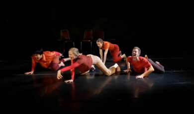 Four performers in red crawl on the ground