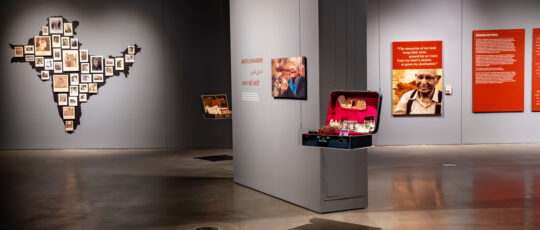 A suitcase is suspended in front of a map overlaid with photos and large red panels with text