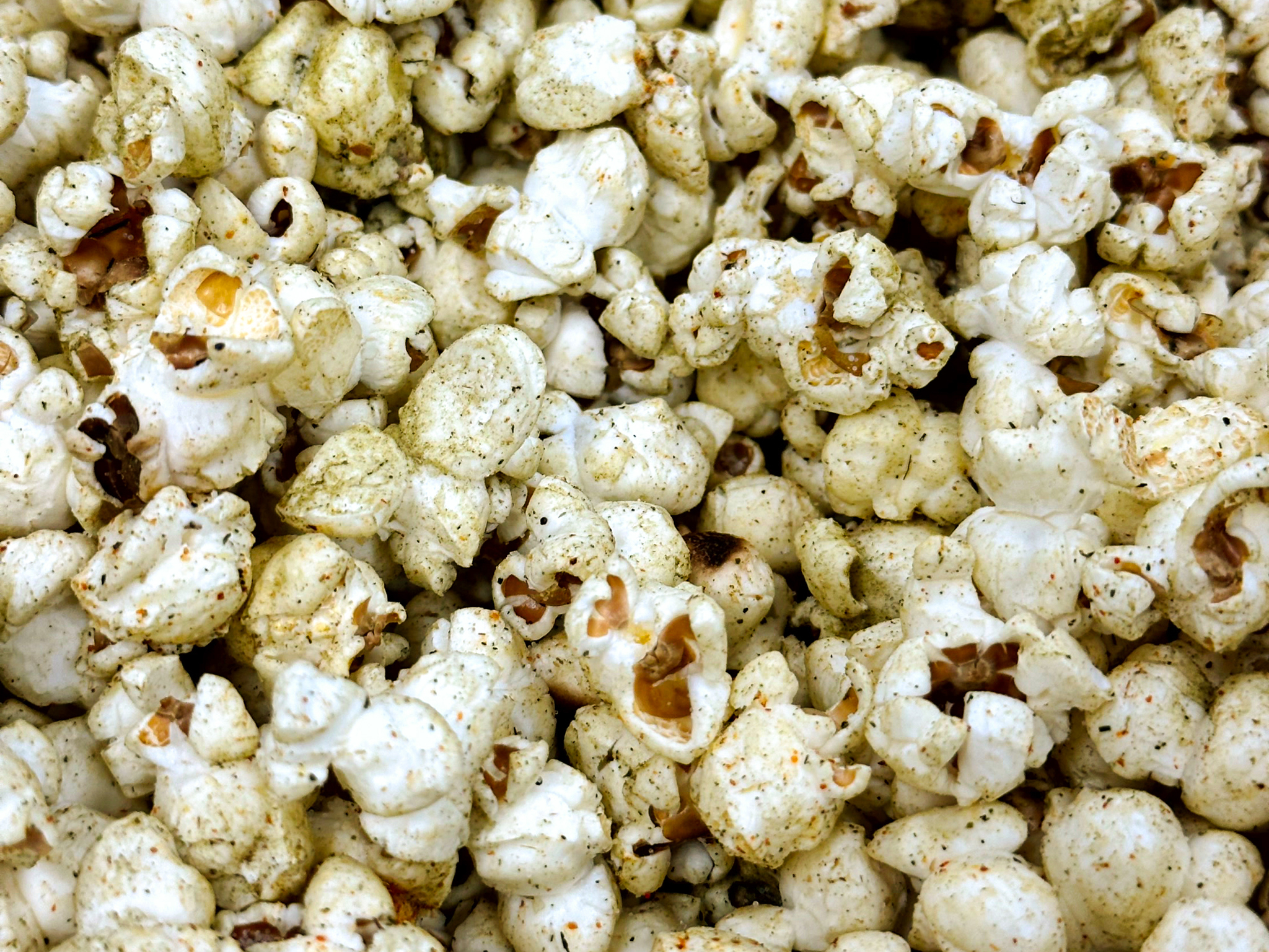 A close up shot of popcorn with green powder sprinkled on top. It is sage popcorn.