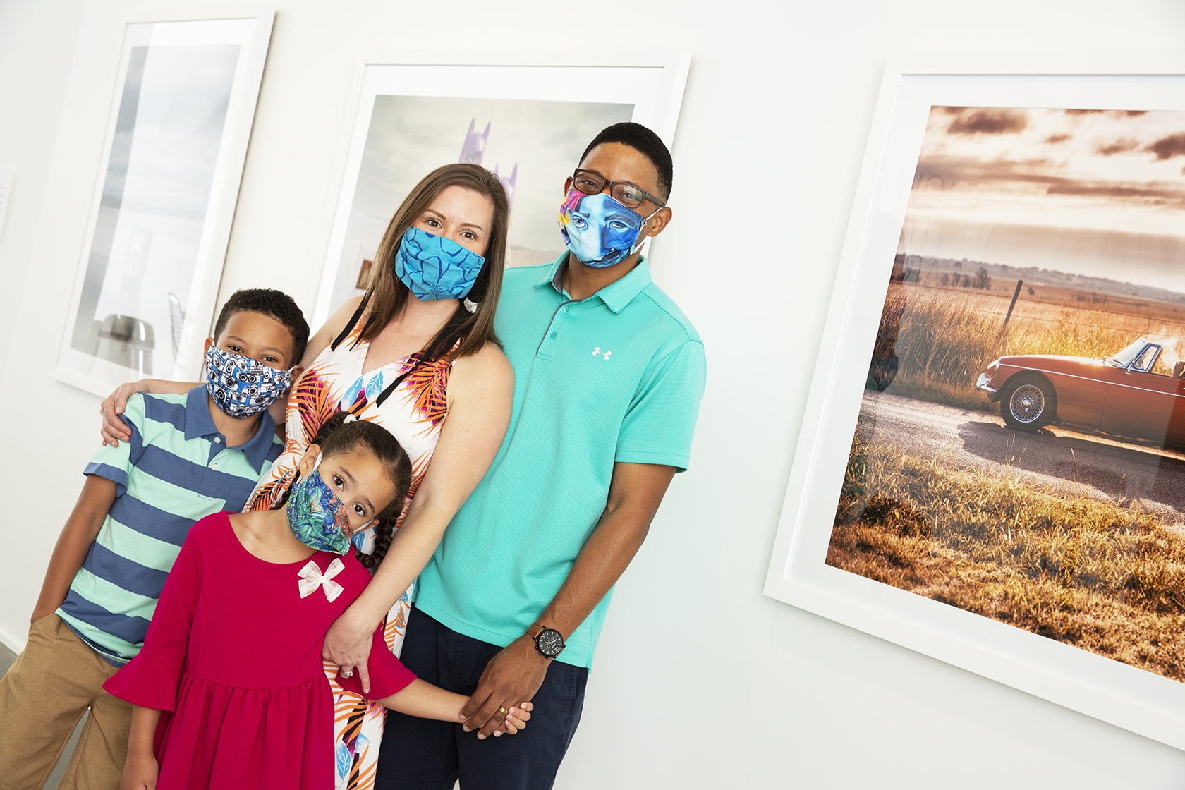 A masked family poses for a photo in an art gallery