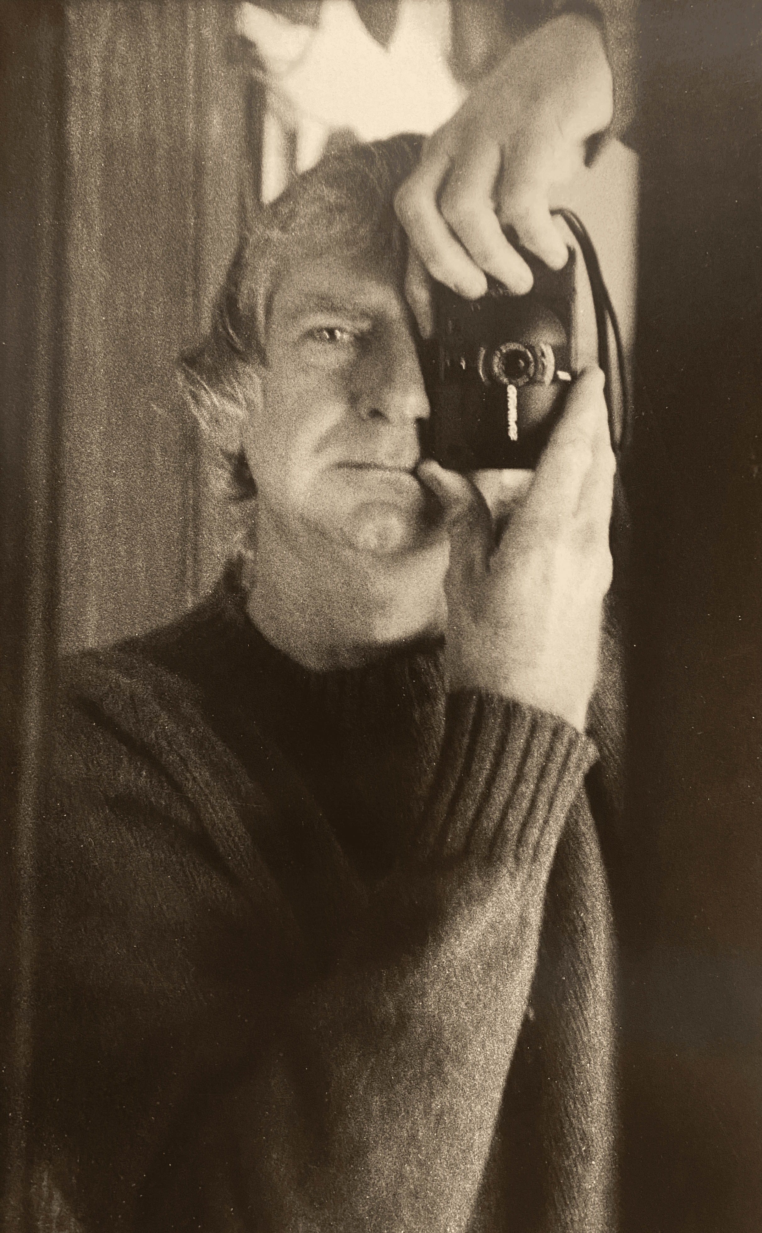 Black and white image of a man taking a photo of himself using a mirror