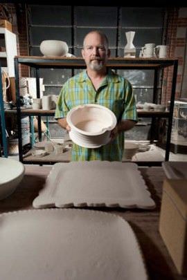 Person with a gray beard and a green shirt poses with a ceramic bowl