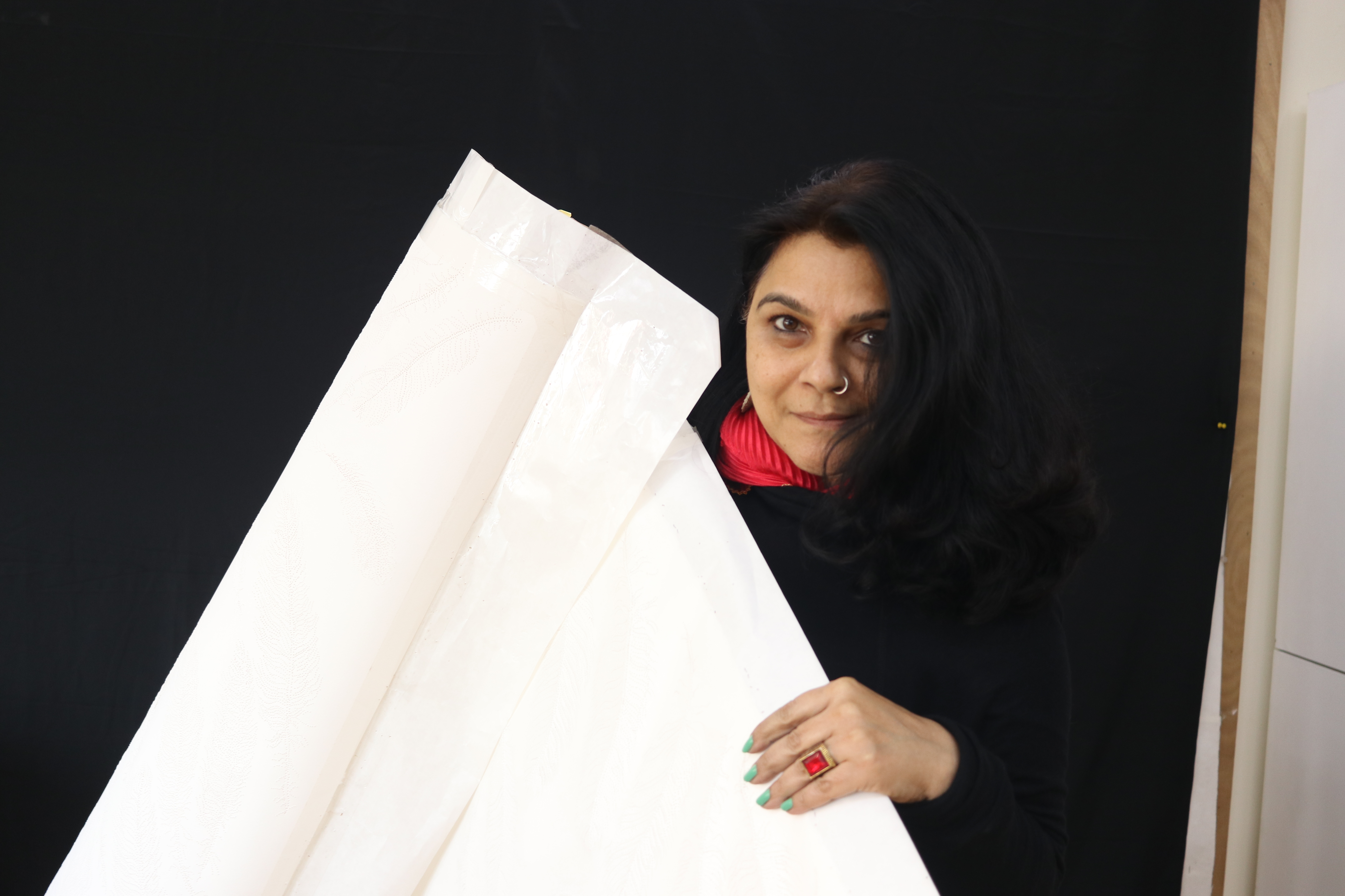A woman dressed in dark colors holds a large white sheet