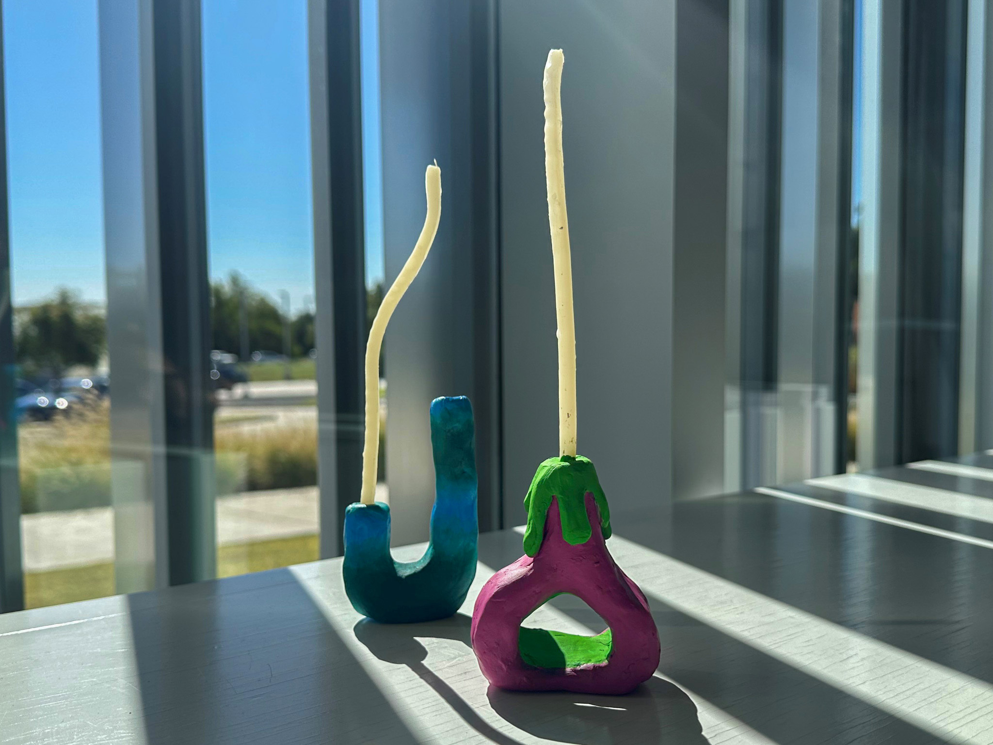 Two colorful and whimsical candleholders with white tapers