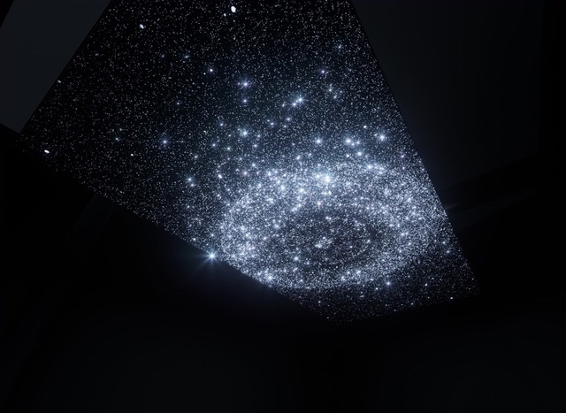 Constellation-like images on a large rectangular LED screen on the ceiling of a dark room