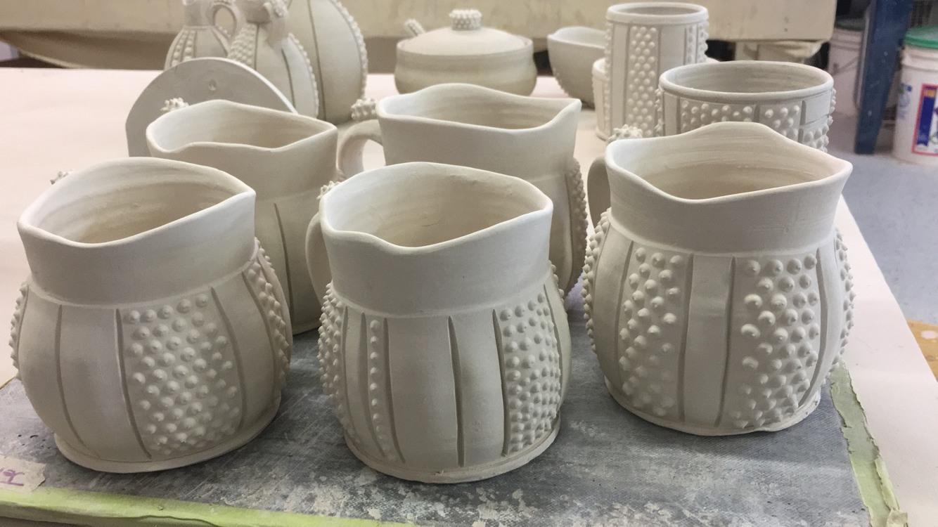 A group of in-progress ceramic mugs