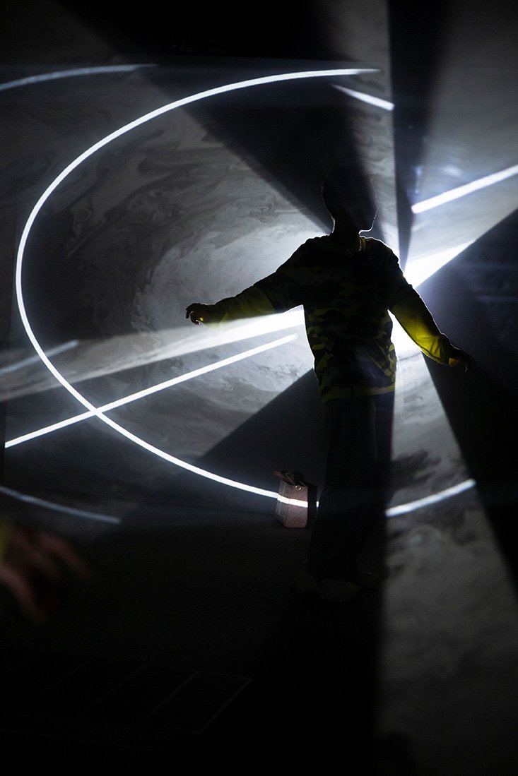 A person poses in a beam of light